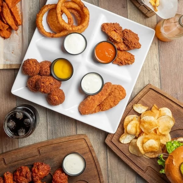 A KX Burger + Beyond platter with onion rings, wings, chicken tenders, and dipping sauces.